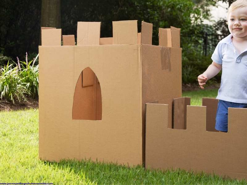 a male child standing by brown Cardboard Castle for 27 Easy Kids Crafts with Recycled Materials (Turn Trash into Treasure)