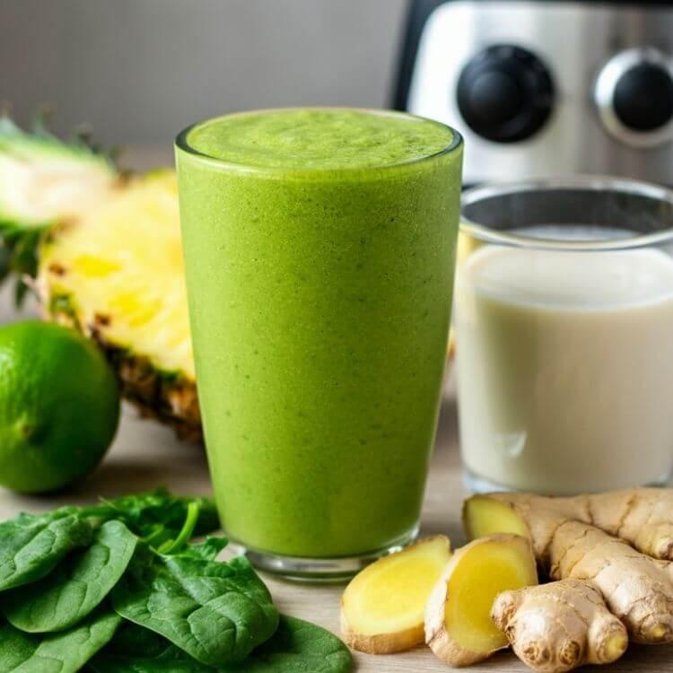 Healthy spinach pineapple smoothie with cucumber, ginger, and lemon in a green drink
